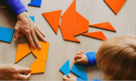 Close up of an adult and child playing with shapes at a table.