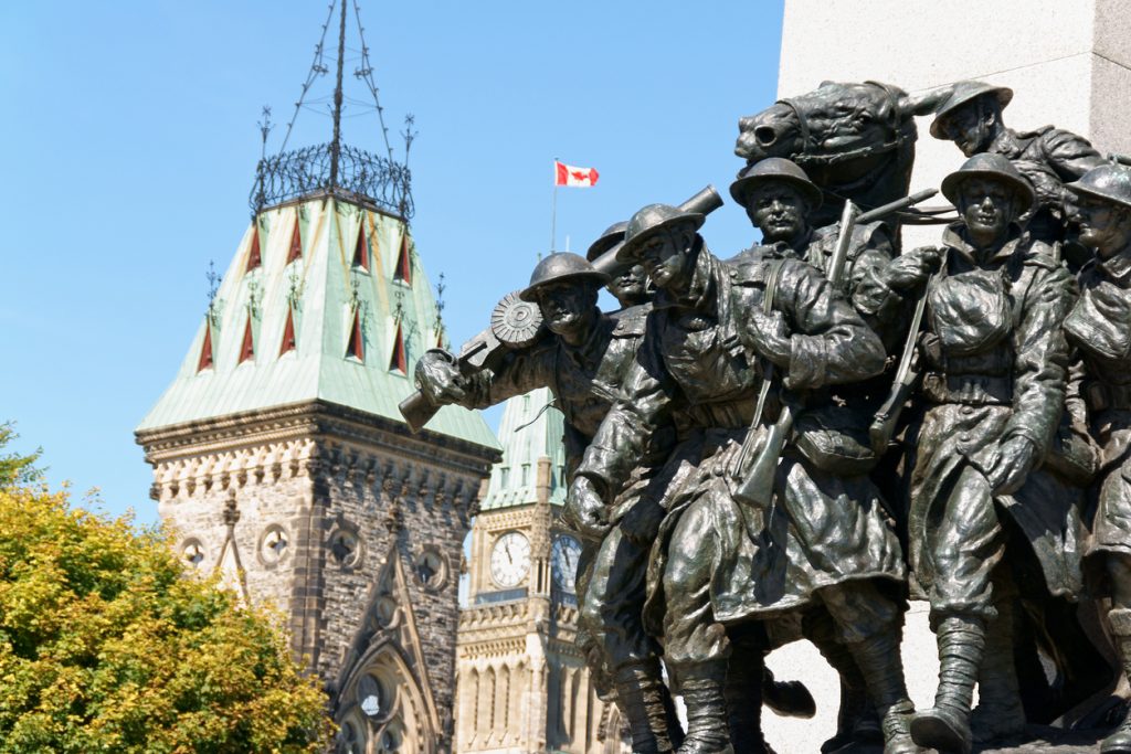 A close-up of the National War Memorial in Ottawa with Canadian Parliament building in the background.