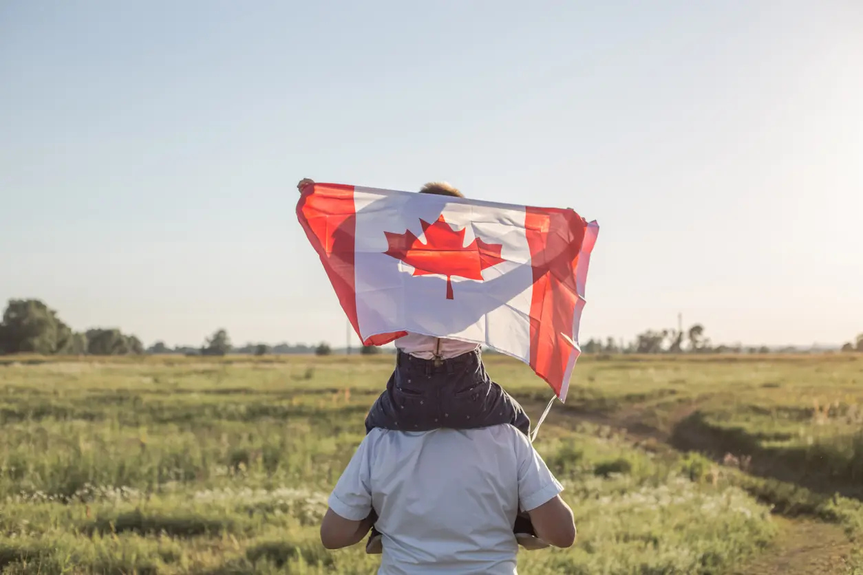 Attractive old senior  man and grahdson holding Canadian Flag. National holiday. Grandpa retiree. Retirement parent